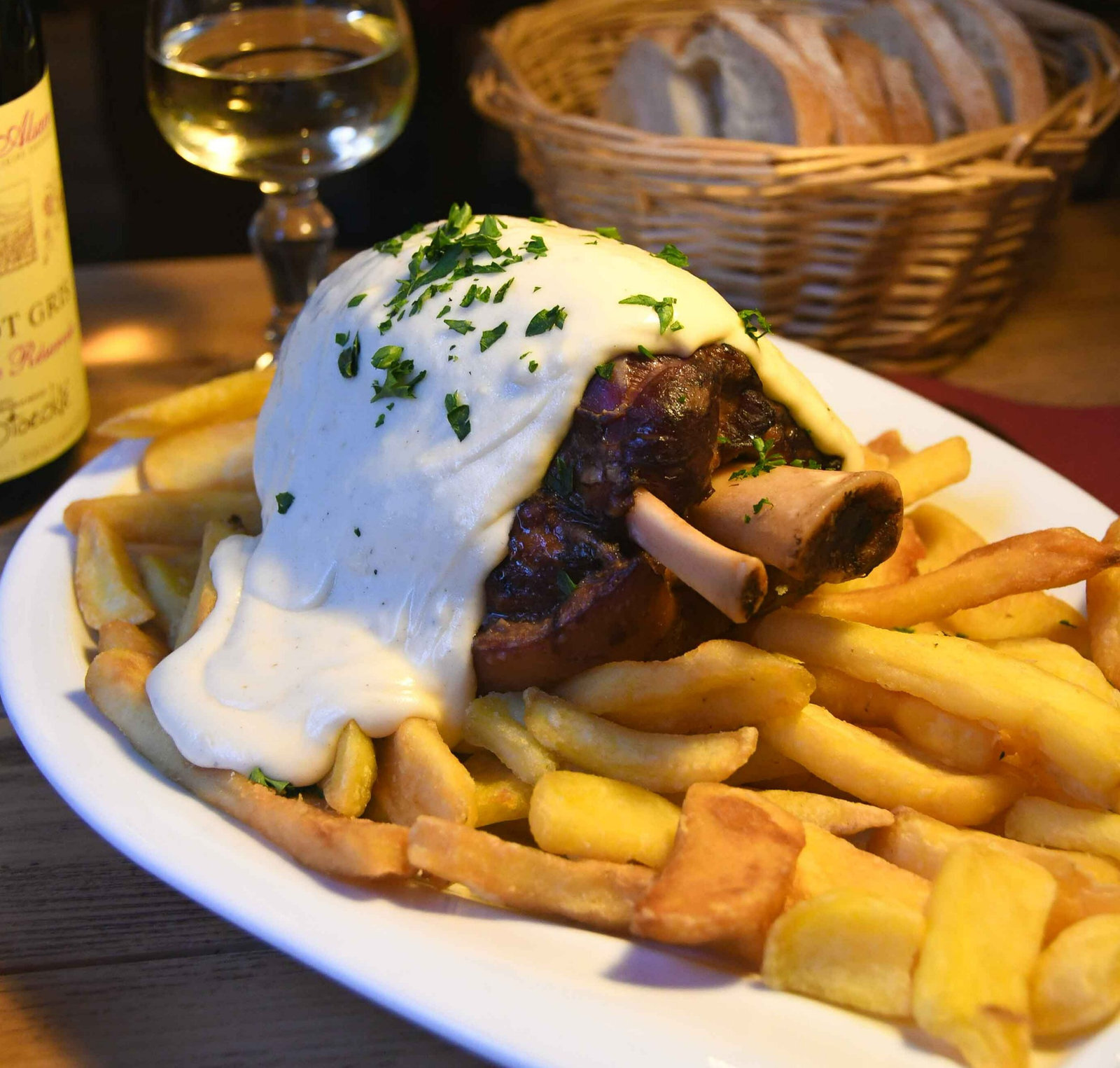 Jambonneau braisé nappé de sauce au munster, sur lit de frites maison