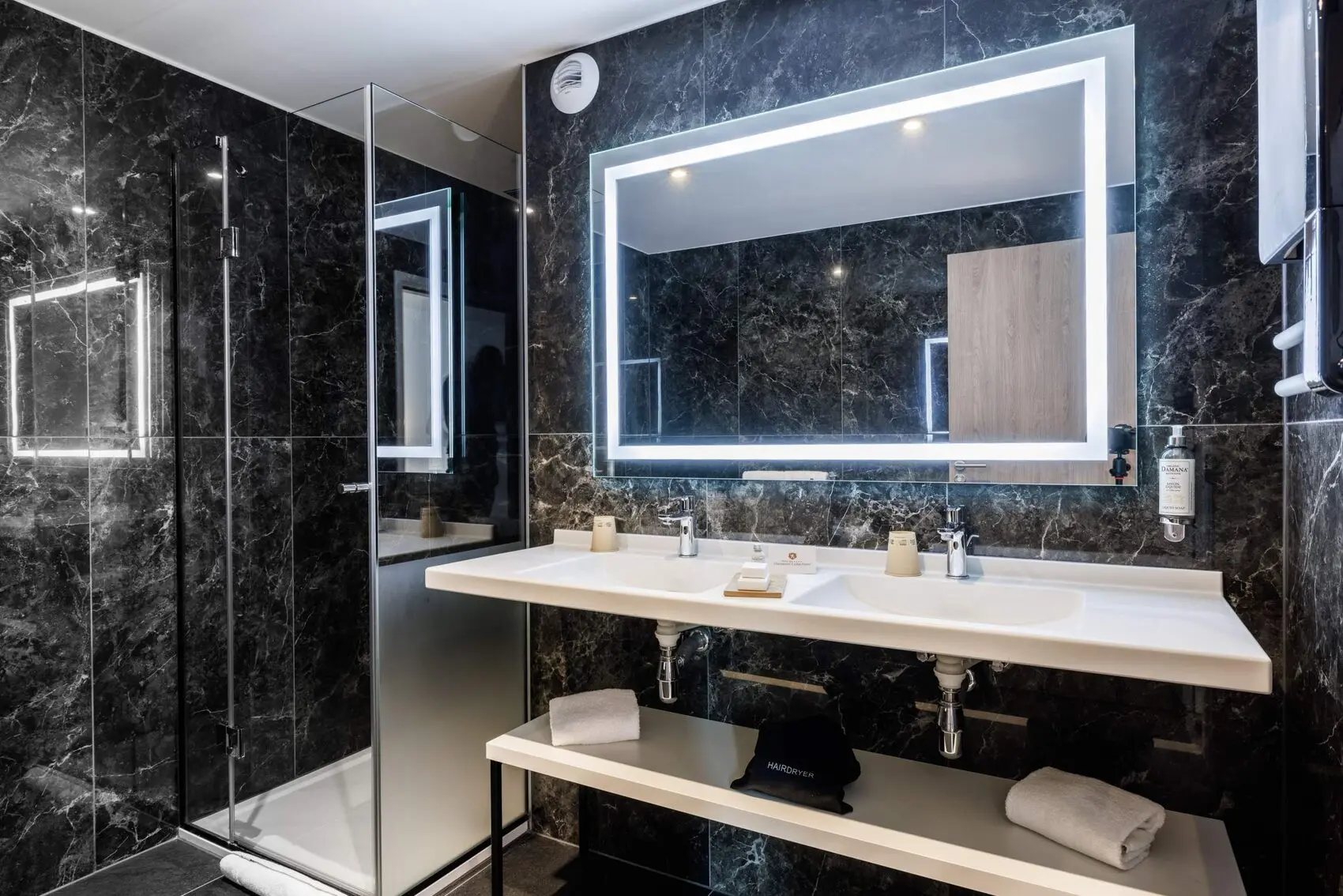 Salle de bain en marbre noir, double vasque et miroirs lumineux