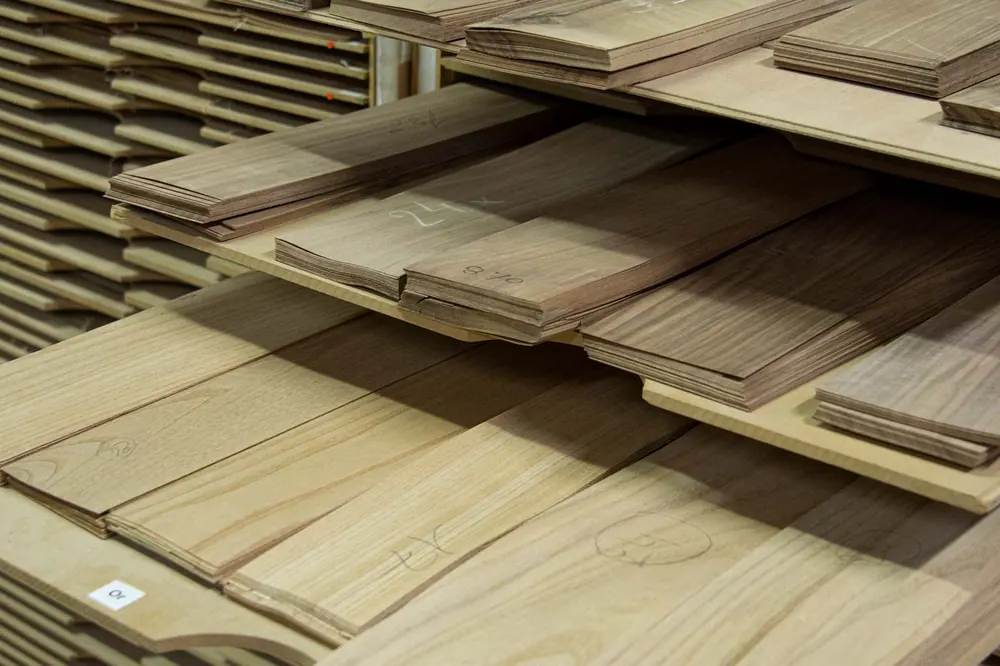 Le placage. Les feuilles de placage sont choisies une à une, puis assemblées au fil de Hotmelt.