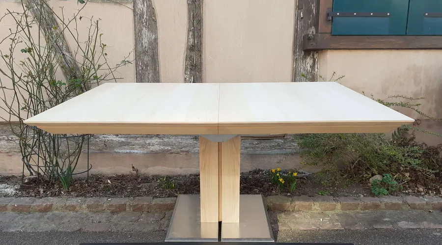 Déco monopied en frêne olivier. Rectangulaire 160 × 110 × H 75,5 cm, s'étirant avec six allonges inox de 50 cm rangées dans la table.
